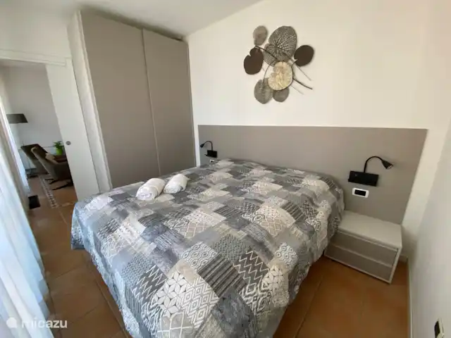 Porto Letizia - Apartamento P6 en Italia, Lagos italianos, Porlezza - apartamento Dormitorio 1: 
Tiene puertas que dan al balcón.
Equipado con 2 camas de somier: 2 veces 0.90 por 2 mtr.
Amplio espacio de almacenamiento en el armario con puertas corredizas y mesitas de noche. 
También calefacción/aire acondicionado en esta habitación.