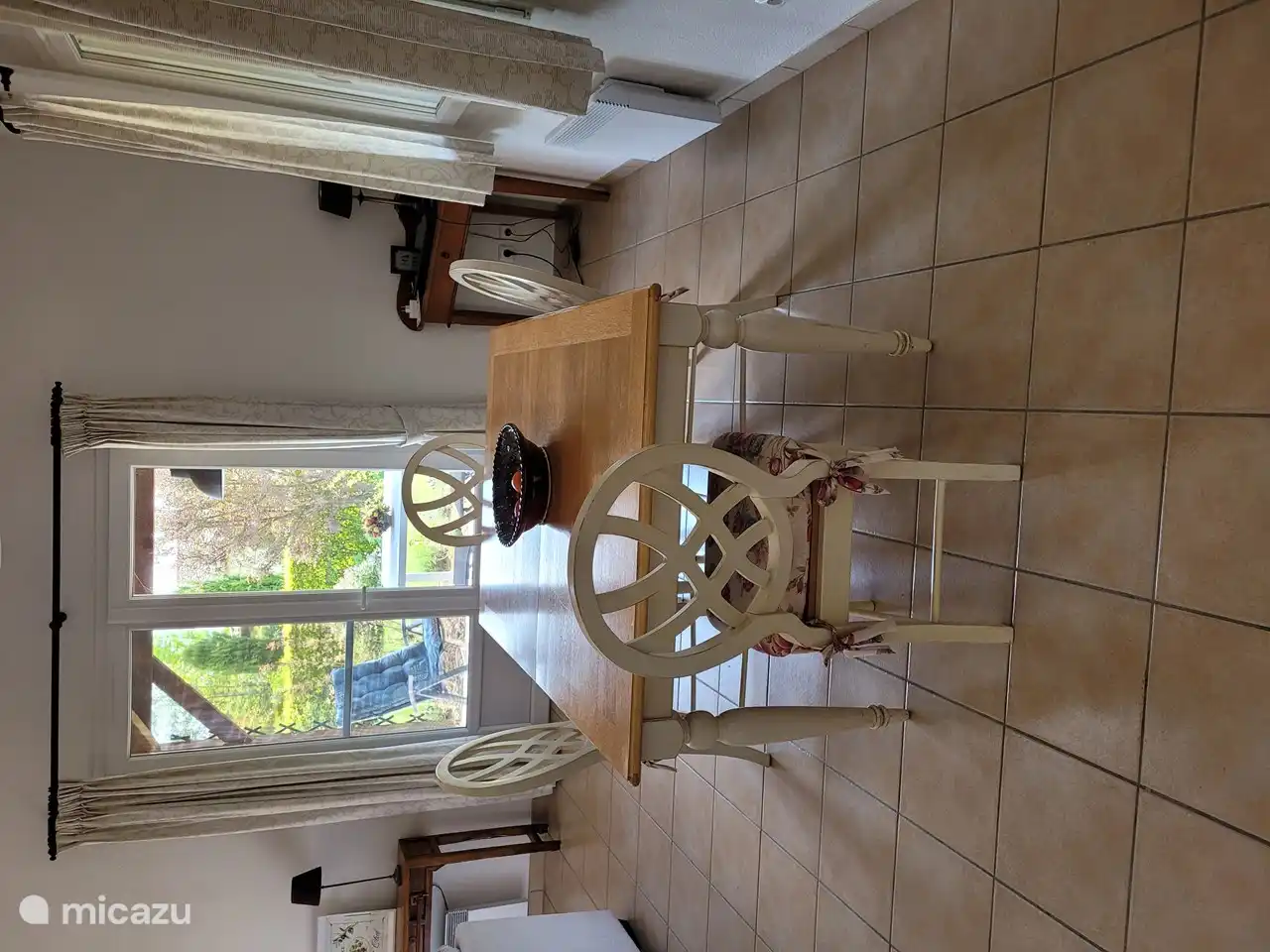 Essbereich mit großem Tisch und Stühlen und im Hintergrund Terrassentüren zur überdachten Terrasse.