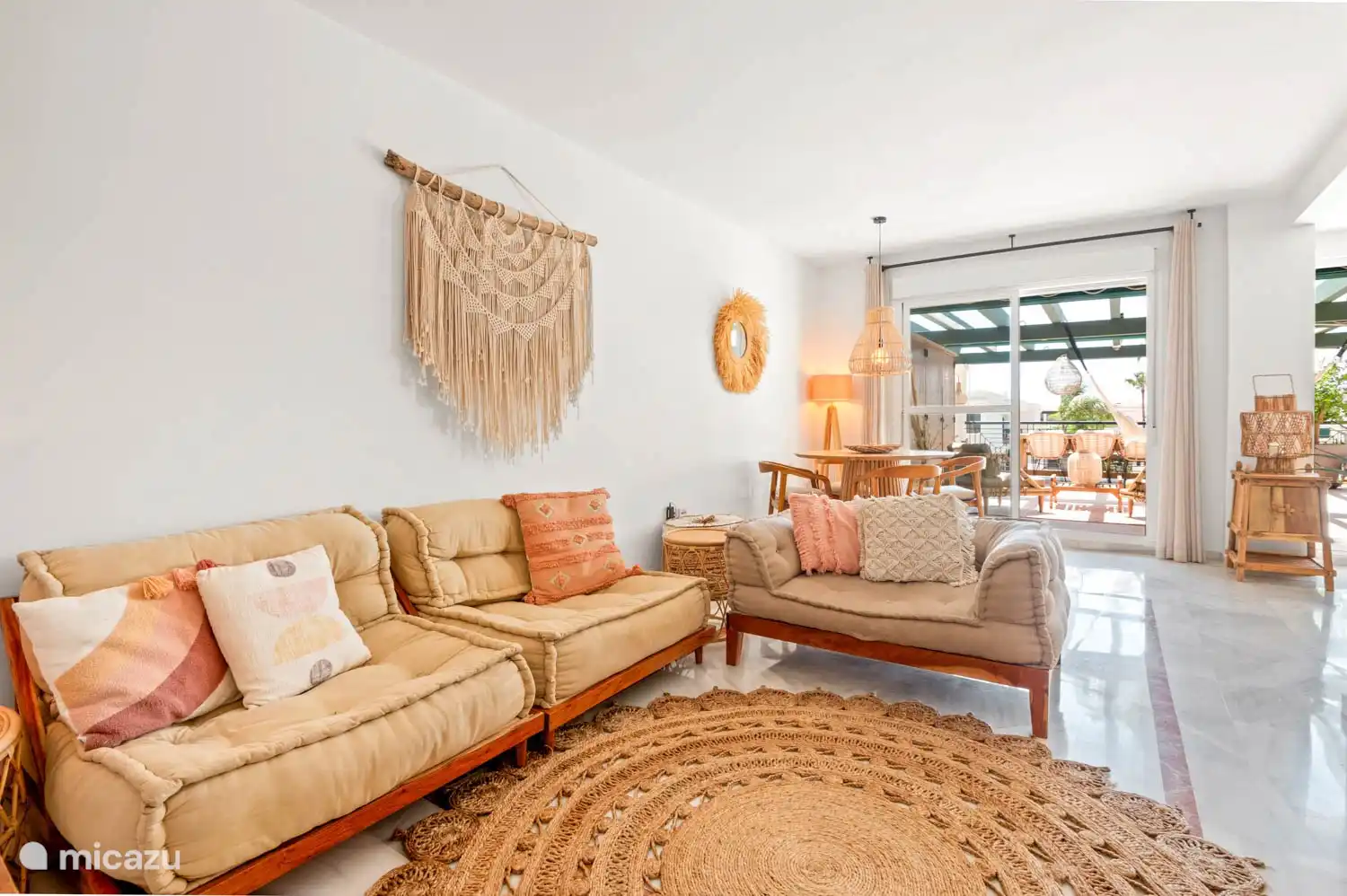 Das offene Wohnzimmer mit zwei Terrassentüren zur Terrasse ist im Ibiza-Lounge-Stil eingerichtet