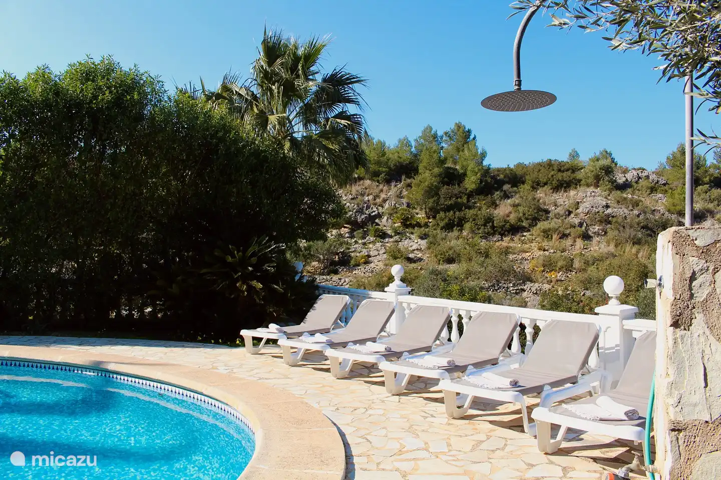 The outdoor shower with the sun beds in the background.