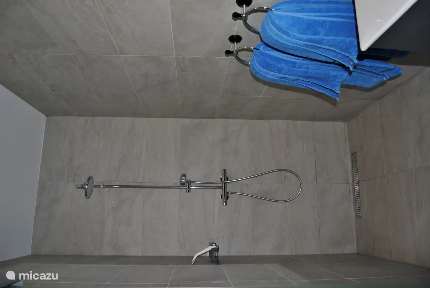 Luxuriöses Badezimmer mit ebenerdiger Regendusche, Waschbecken mit Spiegel.