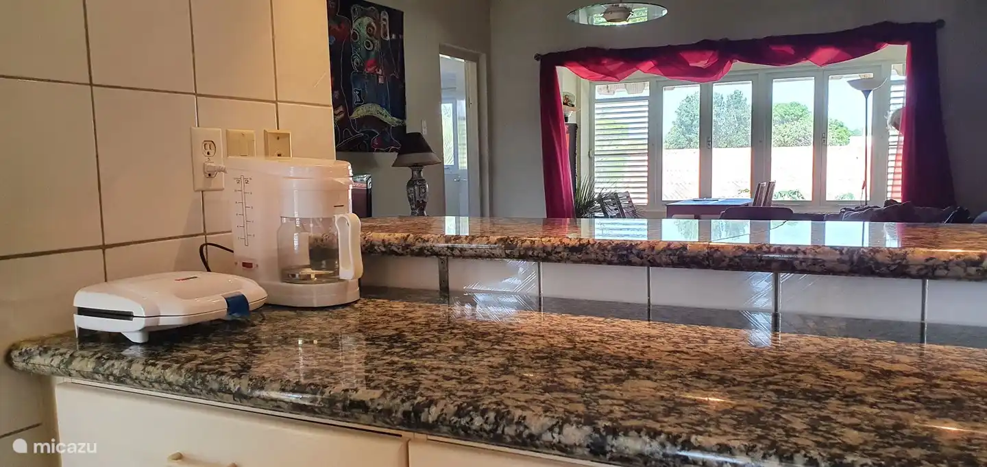 vanuit keuken met eetbar kijk je naar woonkamer en halfopen balkon