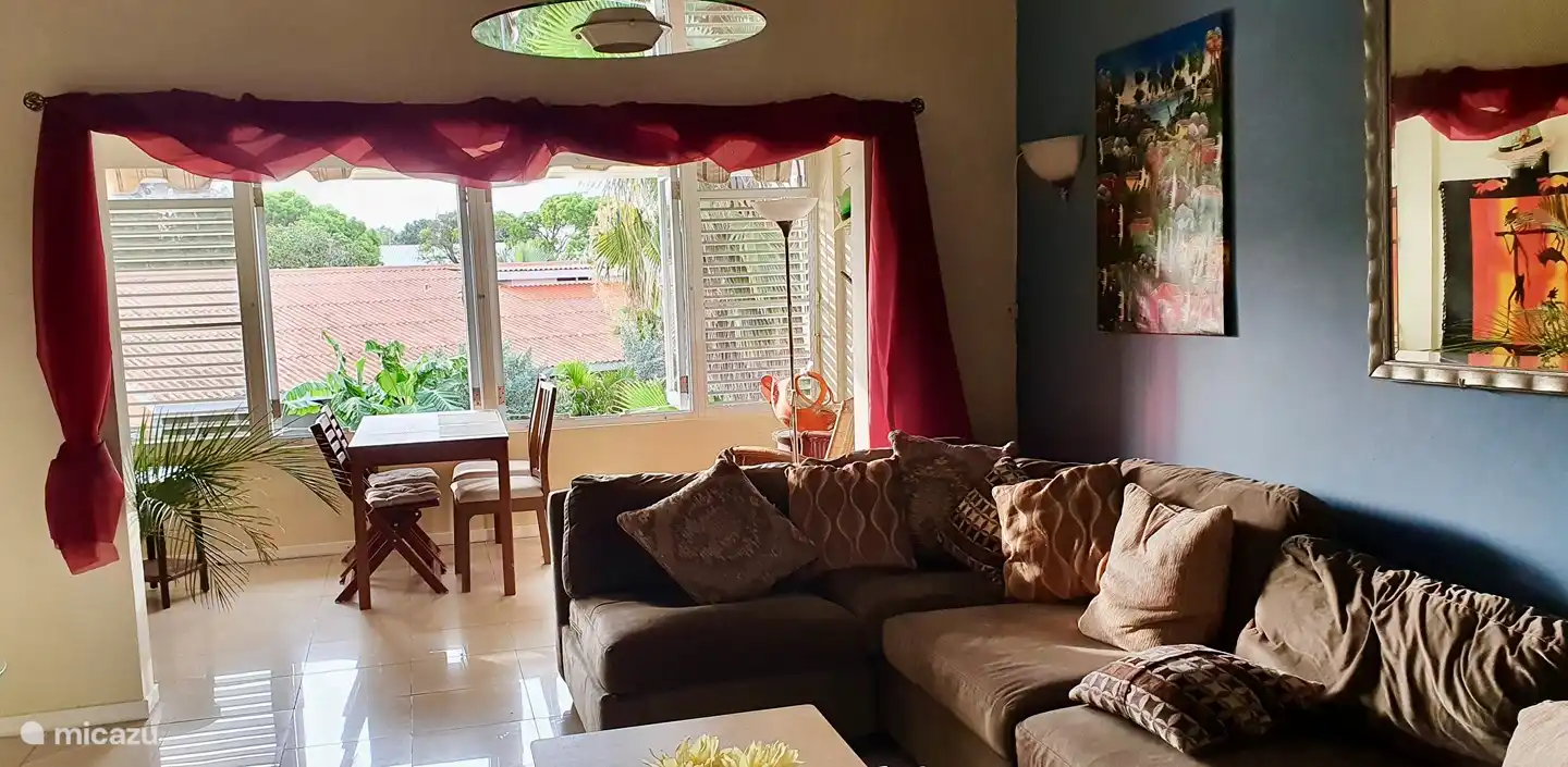 half open balkon met helemaal
openslaande ramen waar ook moskitoframes voor aanwezig zijn. eethoek
met 4 stoelen en schommelstoel