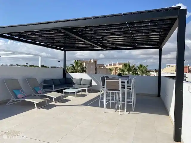 Terrasse sur le toit avec salon et table de bar avec chaises 