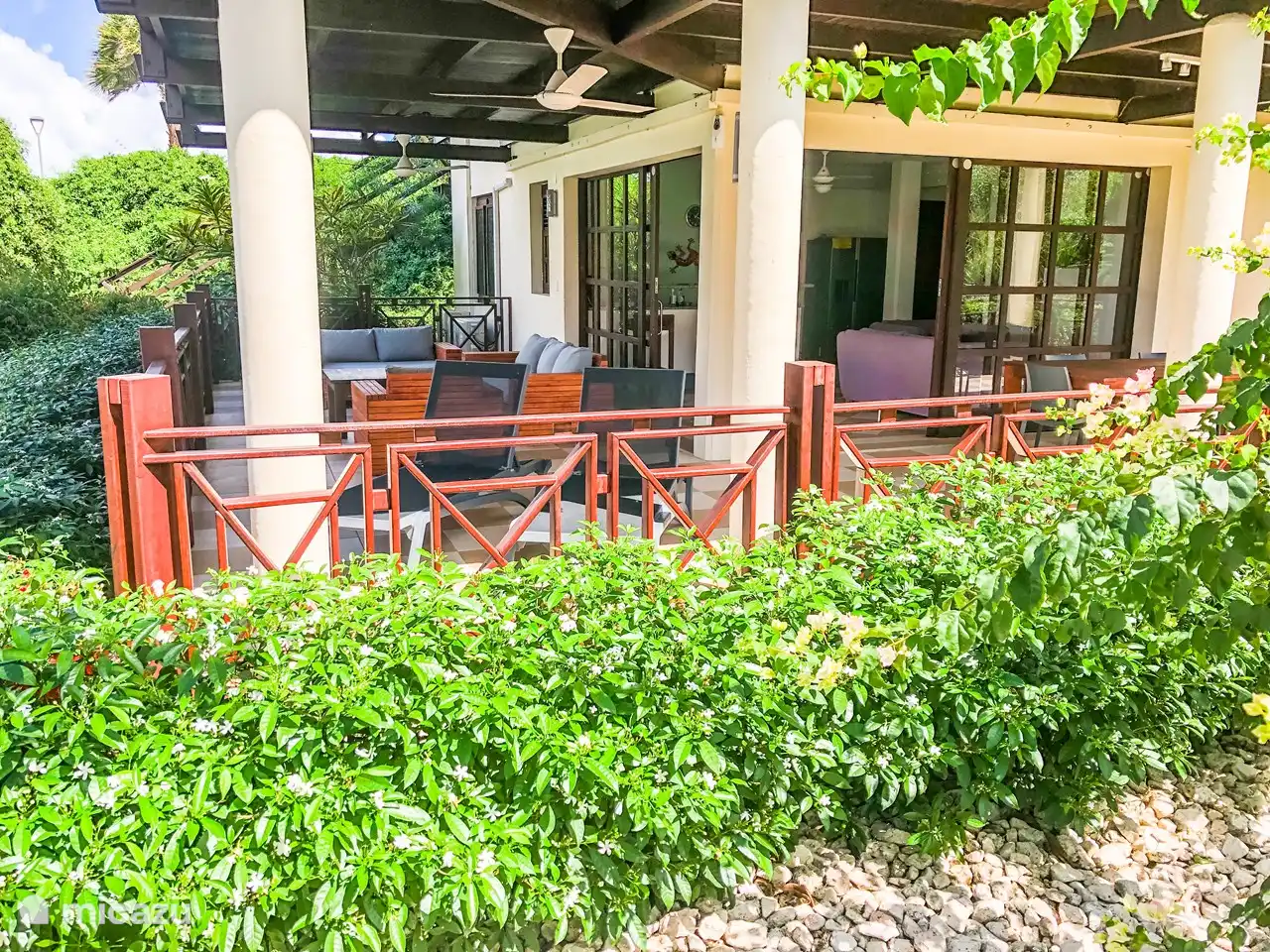 Preciosa y espaciosa terraza cubierta con ventiladores, juego de salón, tumbonas y mesa de comedor.
