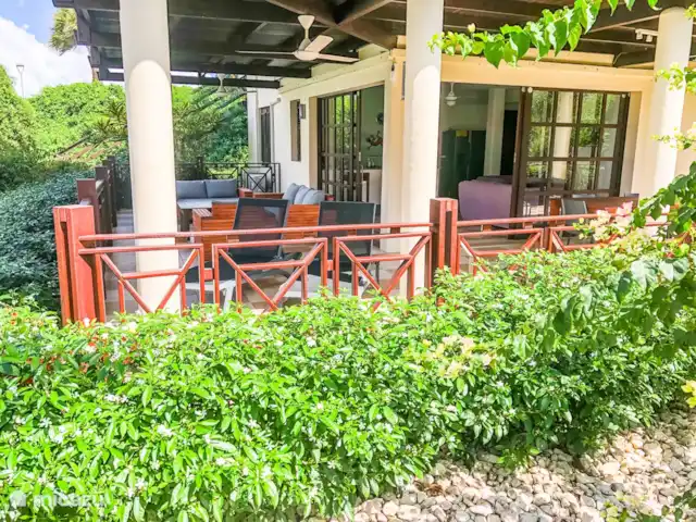 Belle villa à Blue Bay Resort | Curaçao, Curaçao-Centre, Blue Bay - villa Belle terrasse couverte spacieuse avec ventilateurs, salon, chaises longues et table à manger