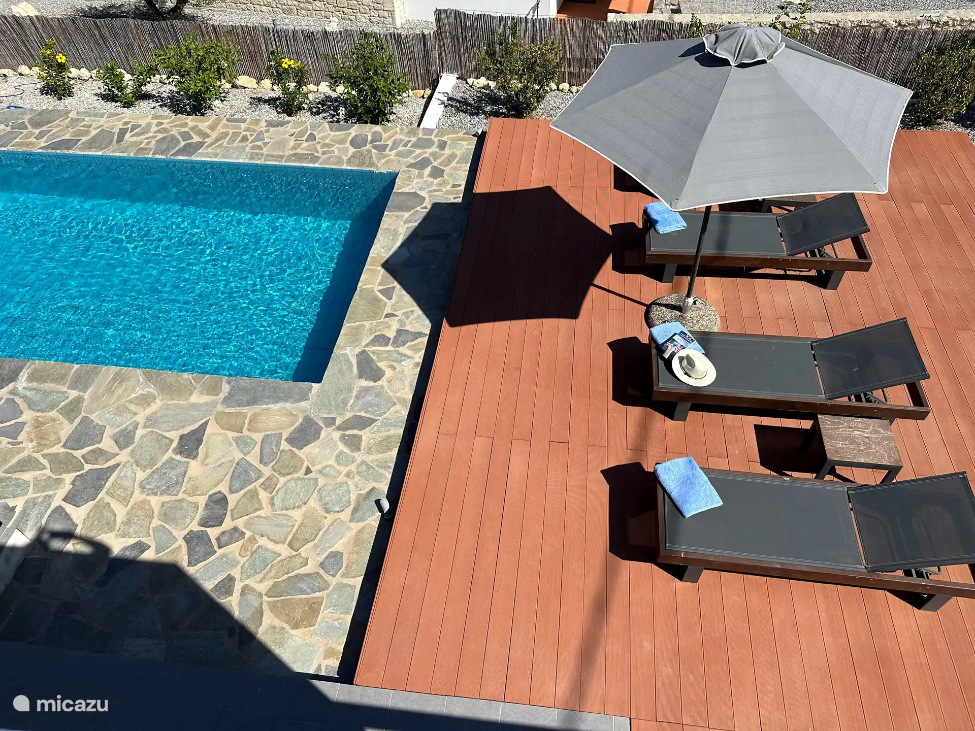 Het zwembad met daarnaast de zonnebedden vanaf het dakterras.