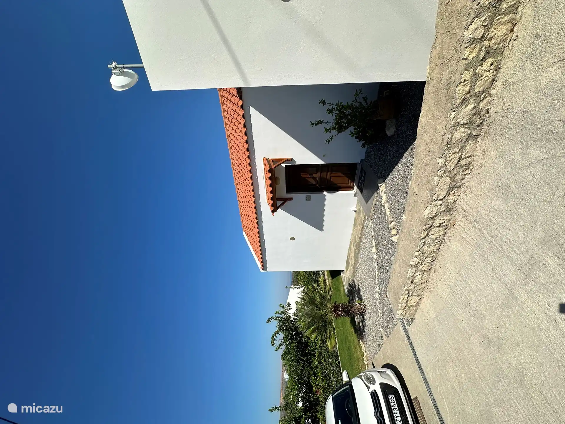 Voordeur van de villa met betonnen oprit en privé parkeerplaats.