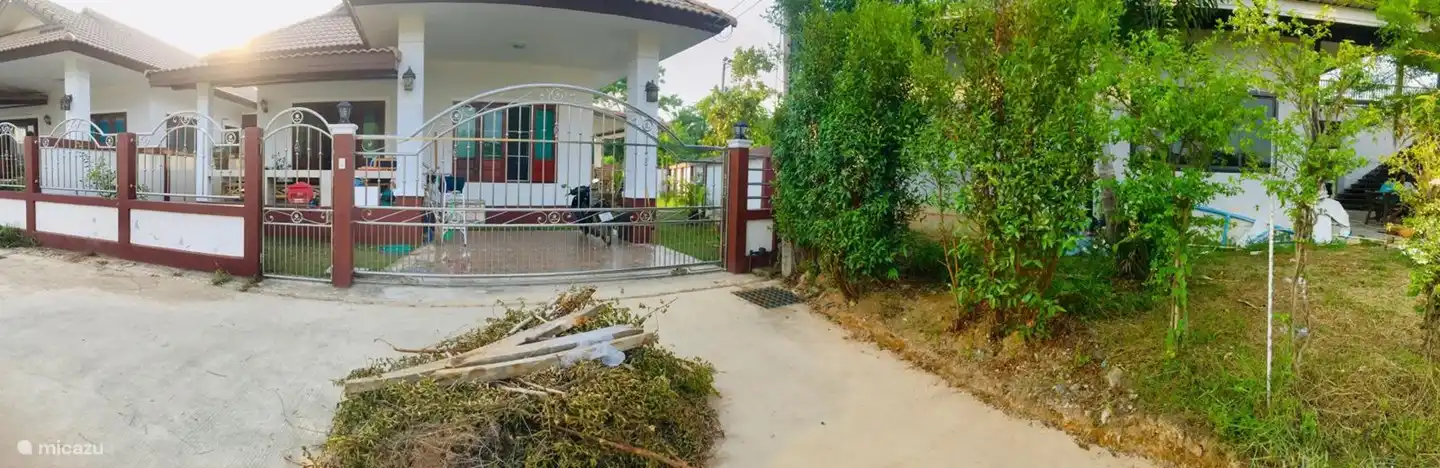 Una foto tomada desde el frente de la casa. La casa se puede cerrar por todas partes con paredes y rejas decorativas. Aparcamiento privado para coches y motos.