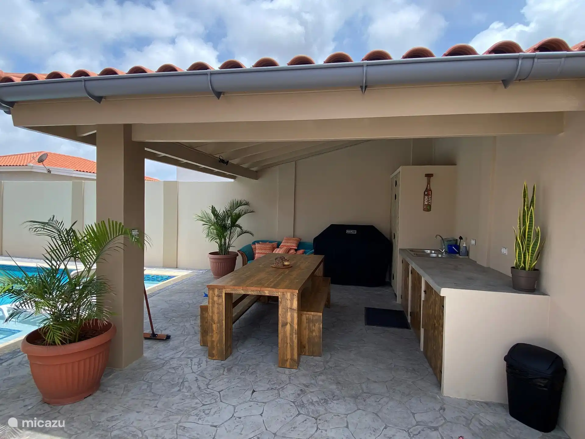 Cuisine extérieure entièrement équipée avec mini-réfrigérateur, barbecue, table à manger avec bancs et canapé séparé sous Cazebo.