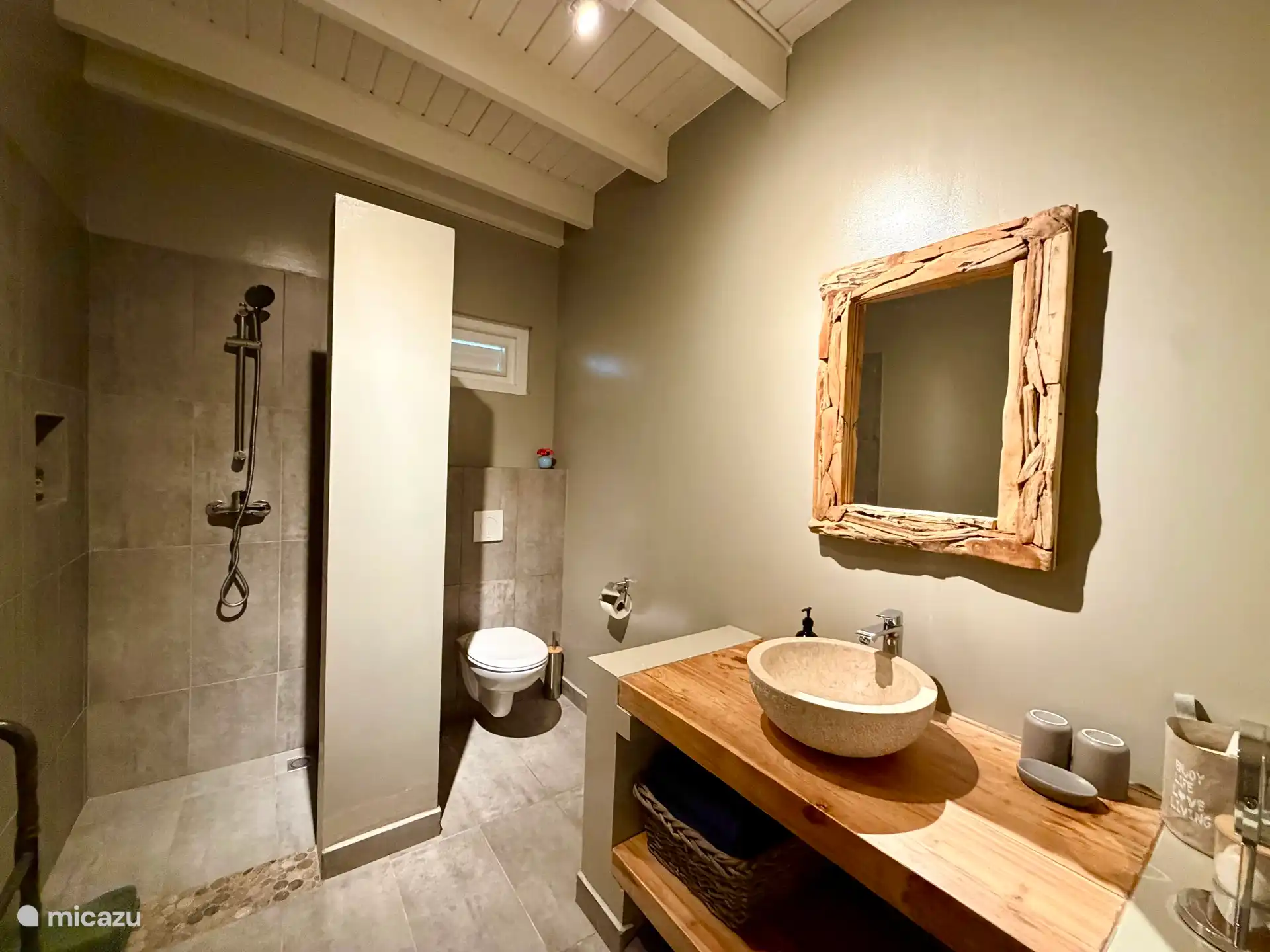 Sfeervol ingerichte badkamer met inloopdouche, toilet, wastafel en grote spiegel. We bieden complimentary handzeep en douchegel van Aruba Aloë Vera aan, en ruim voldoende handdoeken. 