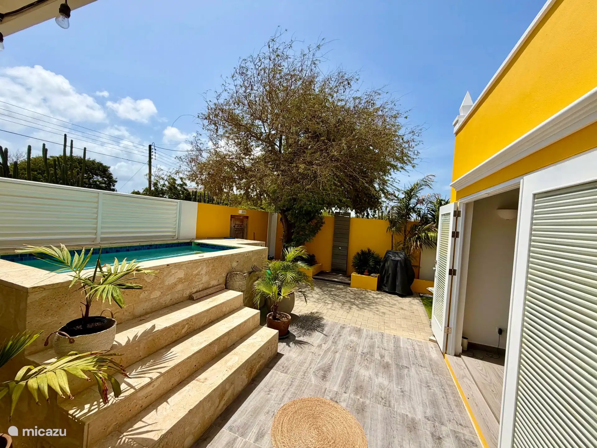 Ruim opgezet terras, aangekleed met planten en palmen. Er staan 2 loungebedden met parasol, buitendouche, een gas-BBQ, en tevens twee strandstoelen, parasol en koelbox om mee te nemen naar het strand