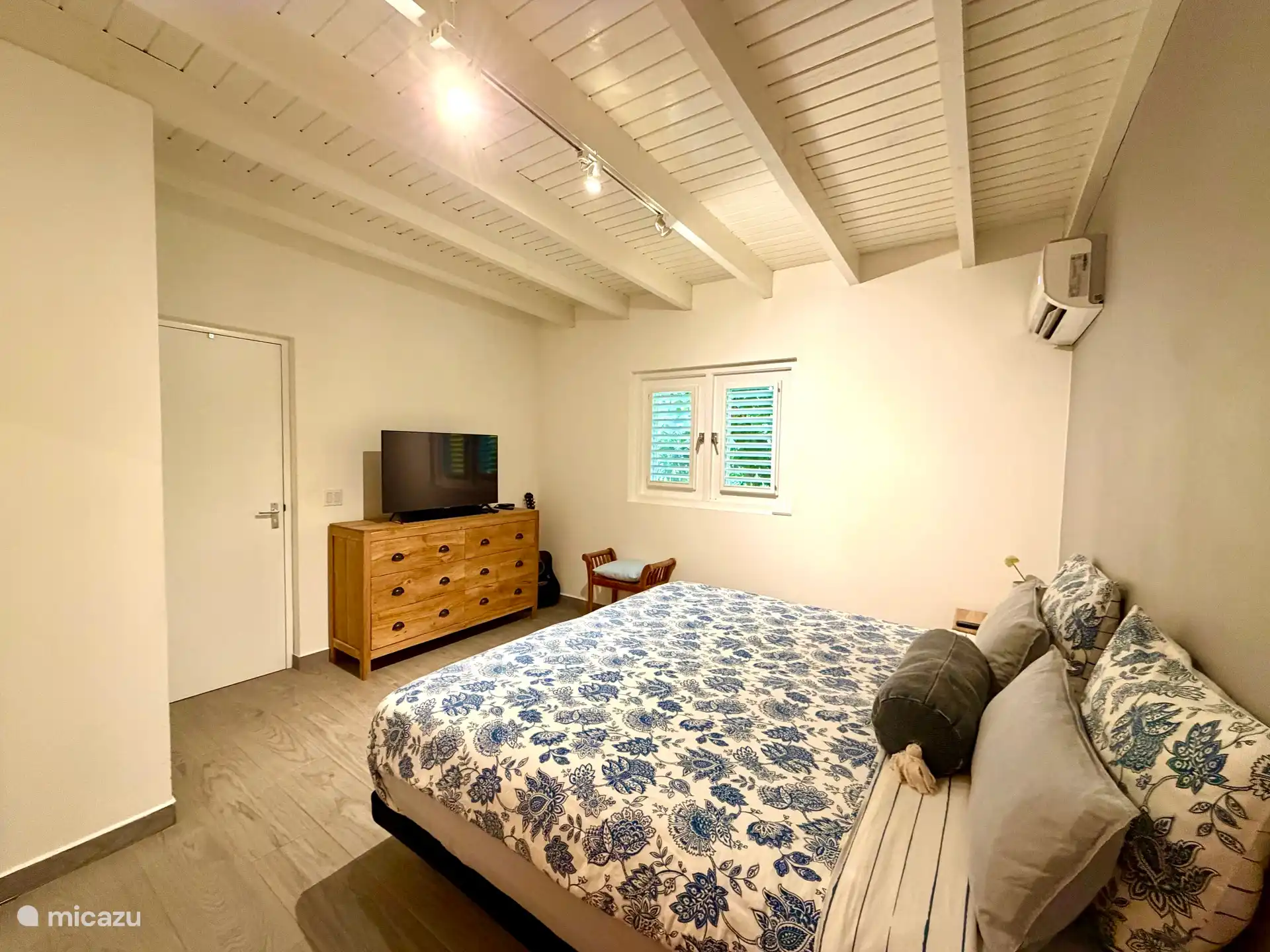 Ruime slaapkamer met airco, luxe verstelbare bedden en tv. Er staat een grote ladenkast en een kledingkast. De slaapkamer is verbonden met de badkamer.