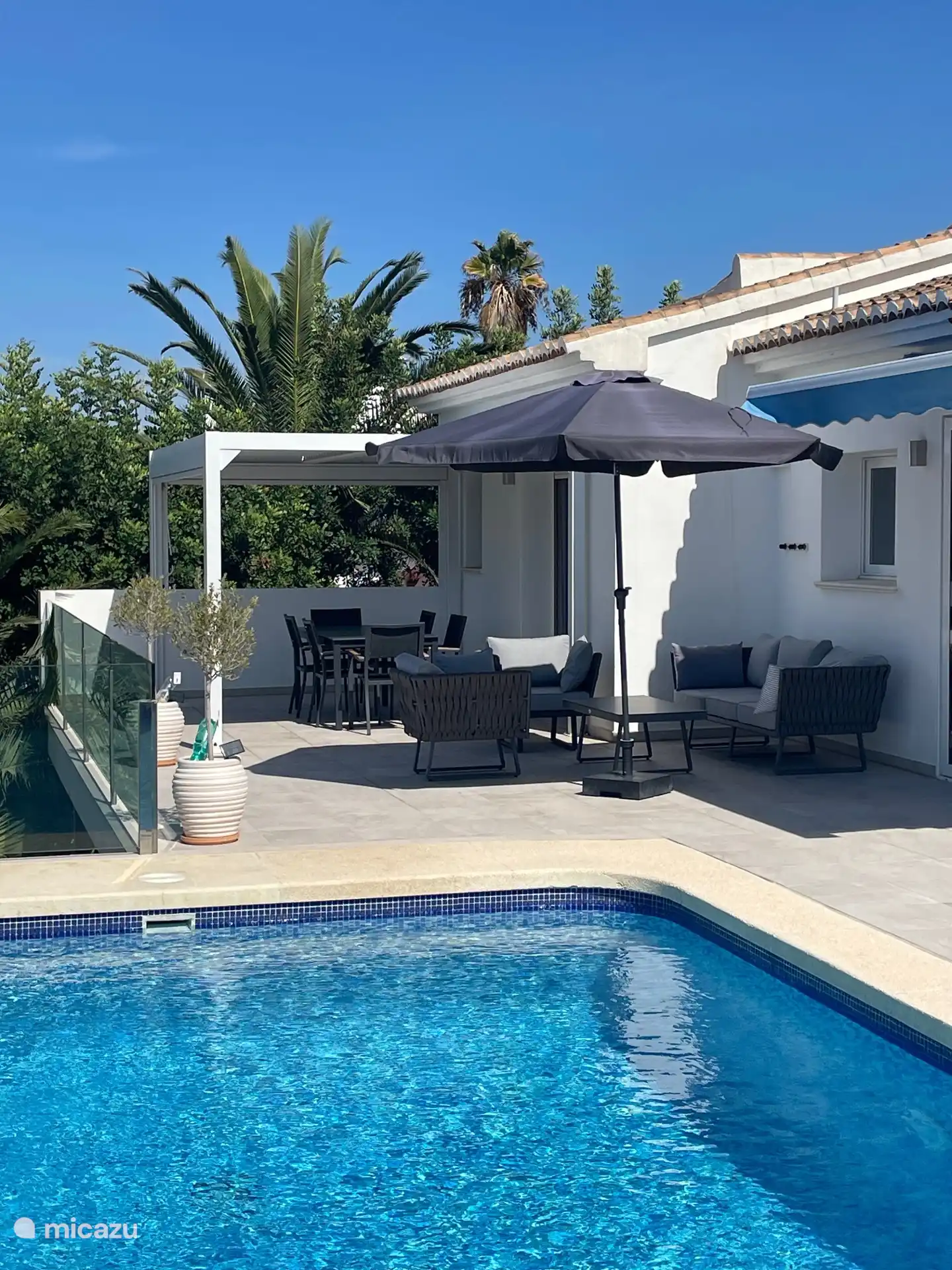 Une pergola spacieuse sur la terrasse avec des brise-soleil fournit toujours de l’ombre ou une protection contre le vent. Il y a aussi un salon moderne.