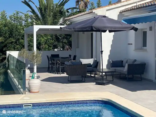 Location de Vacances Espagne, Costa Blanca, Benitachell, villa - Maison Quercia Une pergola spacieuse sur la terrasse avec des brise-soleil fournit toujours de l’ombre ou une protection contre le vent. Il y a aussi un salon moderne.