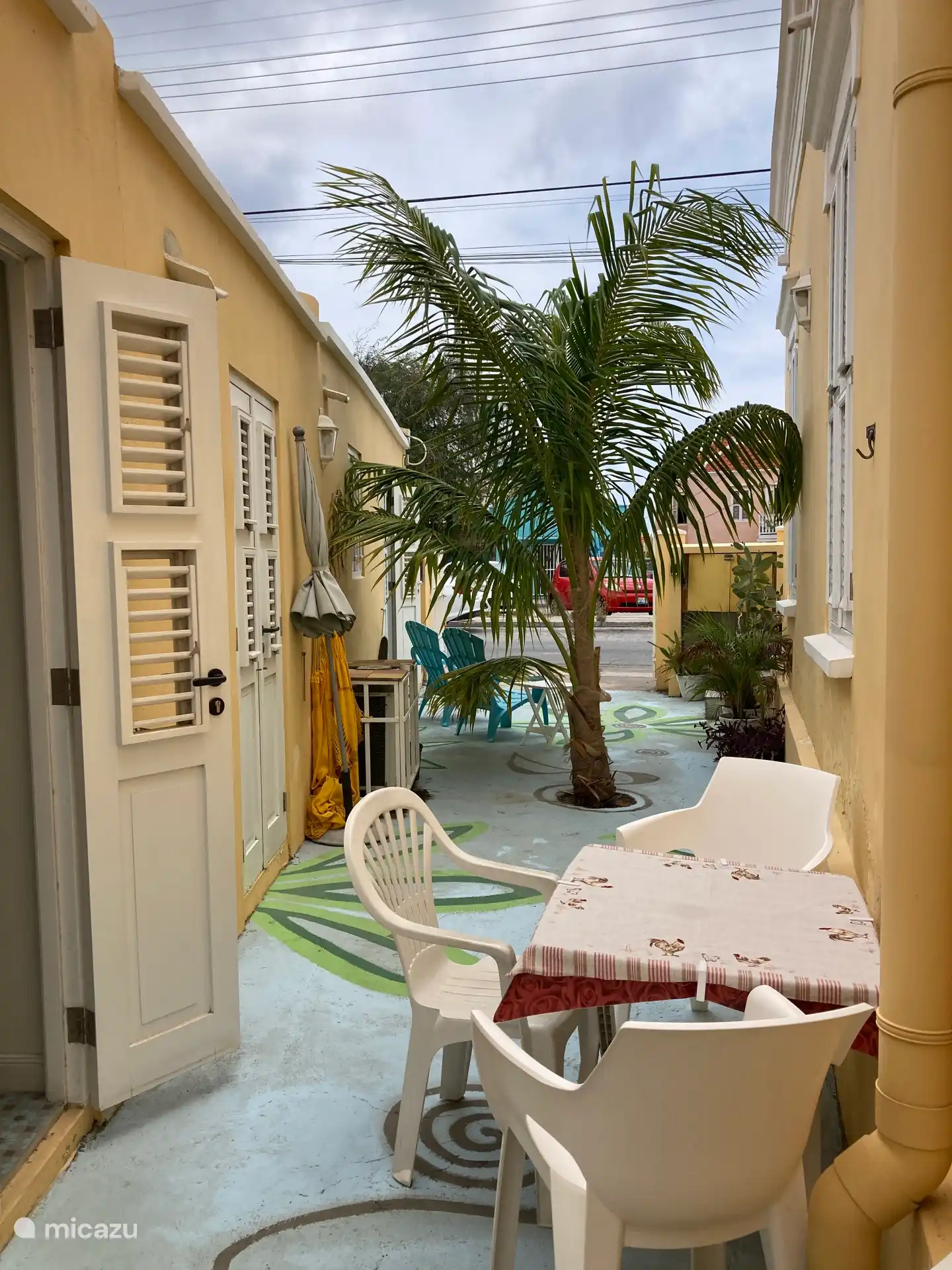 Buiten ontbijten, tafel met 4 stoelen. Parasol en hangmat. Doorkijk naar voorzijde terras. Iedere kamer heeft louvredeuren die uitkomen op het terras. 