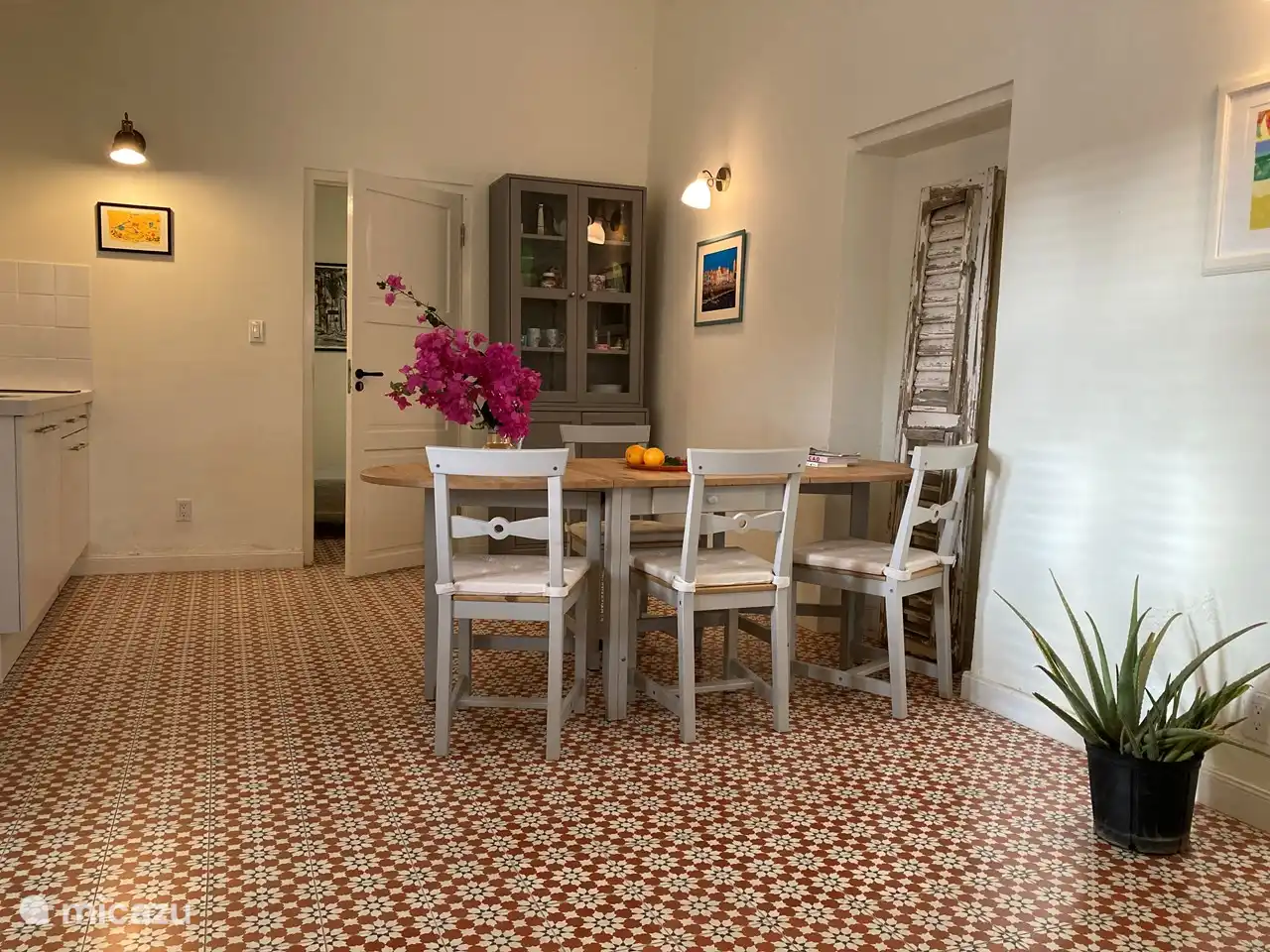 Wohn- und Esszimmer mit großem Tisch und 4 Stühlen und Vitrine mit Küchenutensilien.