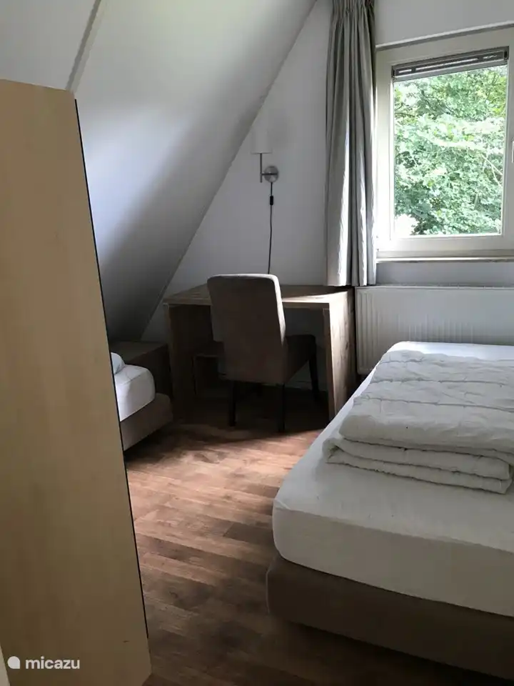 Schlafzimmer mit 2 Einzelbetten und Kleiderschrank und einem Schreibtisch.