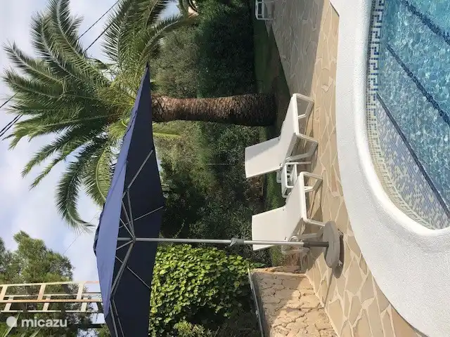 Terrasse piscine équipée de transats et parasols.