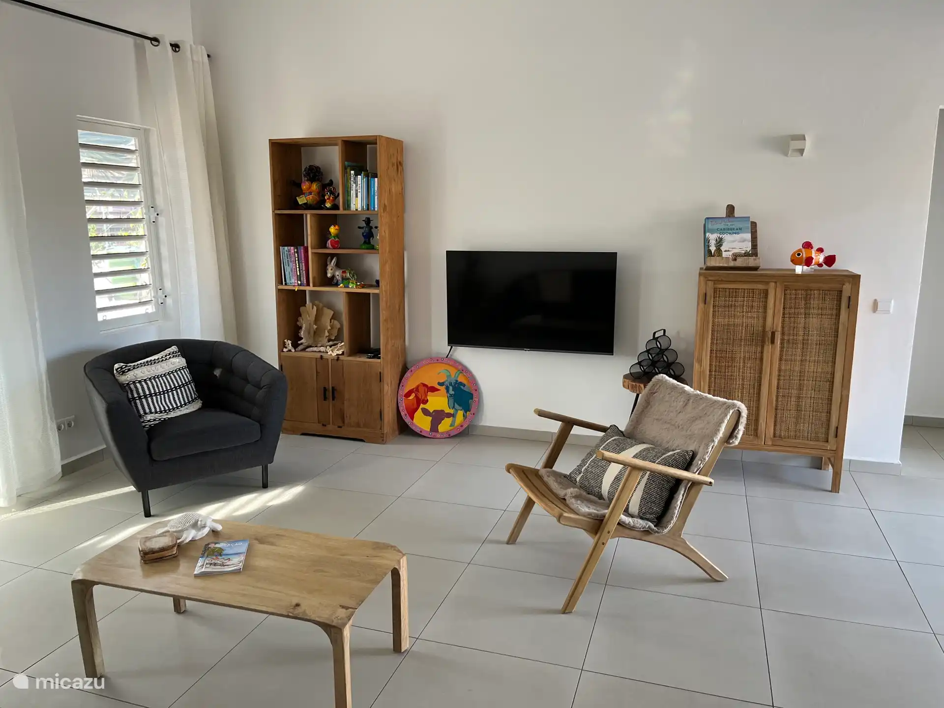 Wohnzimmer mit Smart-TV, Sitzgelegenheiten, Bücherregal und Schrank mit zusätzlichem Vorrat an Bettwäsche. 