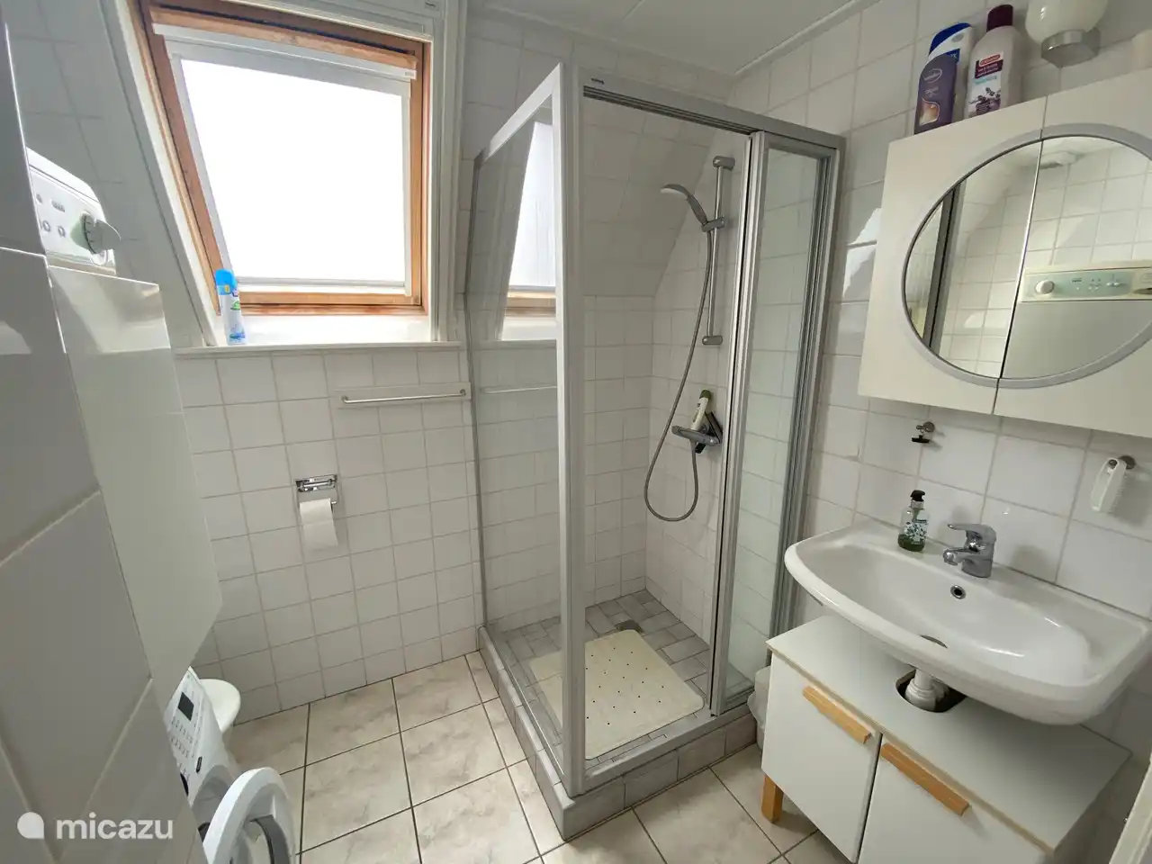 Badezimmer mit Dusche, WC und Waschbecken, Waschmaschine und Trockner.