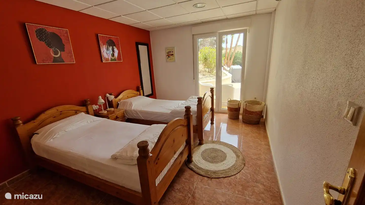 Chambre 3 au rez-de-chaussée avec portes patio donnant sur la piscine. Cette chambre dispose de 2 lits simples et d'une grande armoire intégrée.