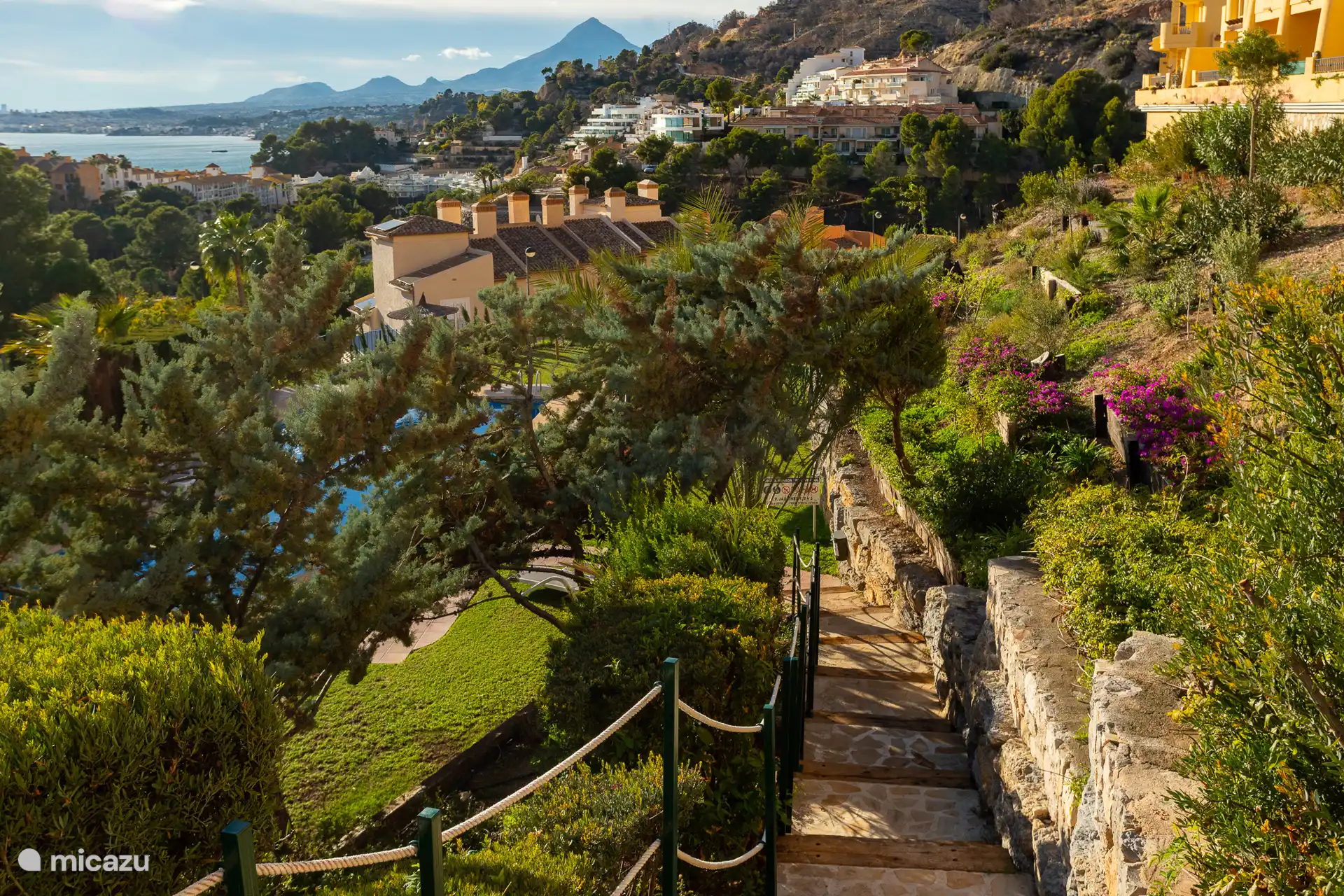 De fraai aangelegde tuin verbind de twee zwembaden met elkaar via een trap. Hier loop je naar het lager gelegen zwembad en kijk je uit over de baai. 