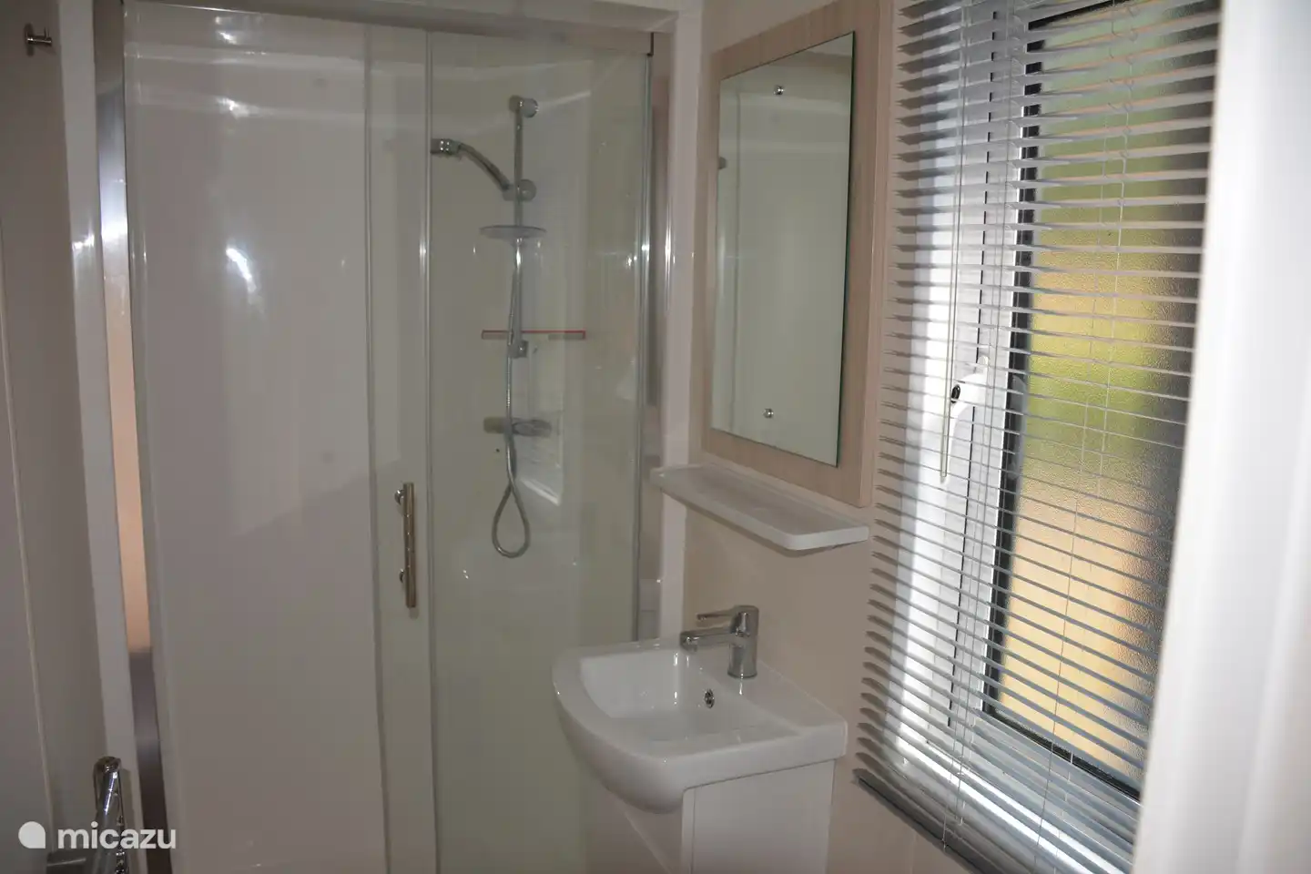 De badkamer is voorzien van een douche cabine, wastafel en toilet. 