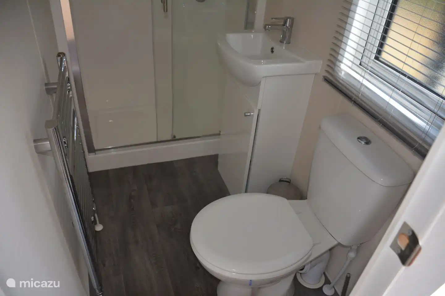 De badkamer is voorzien van een douche cabine, wastafel en toilet. 