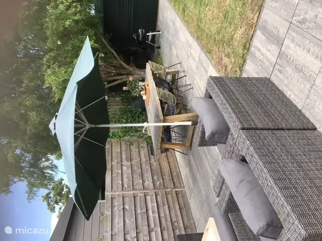 Terraza con juego de salón, sombrillas y mesa de comedor y BBQ.