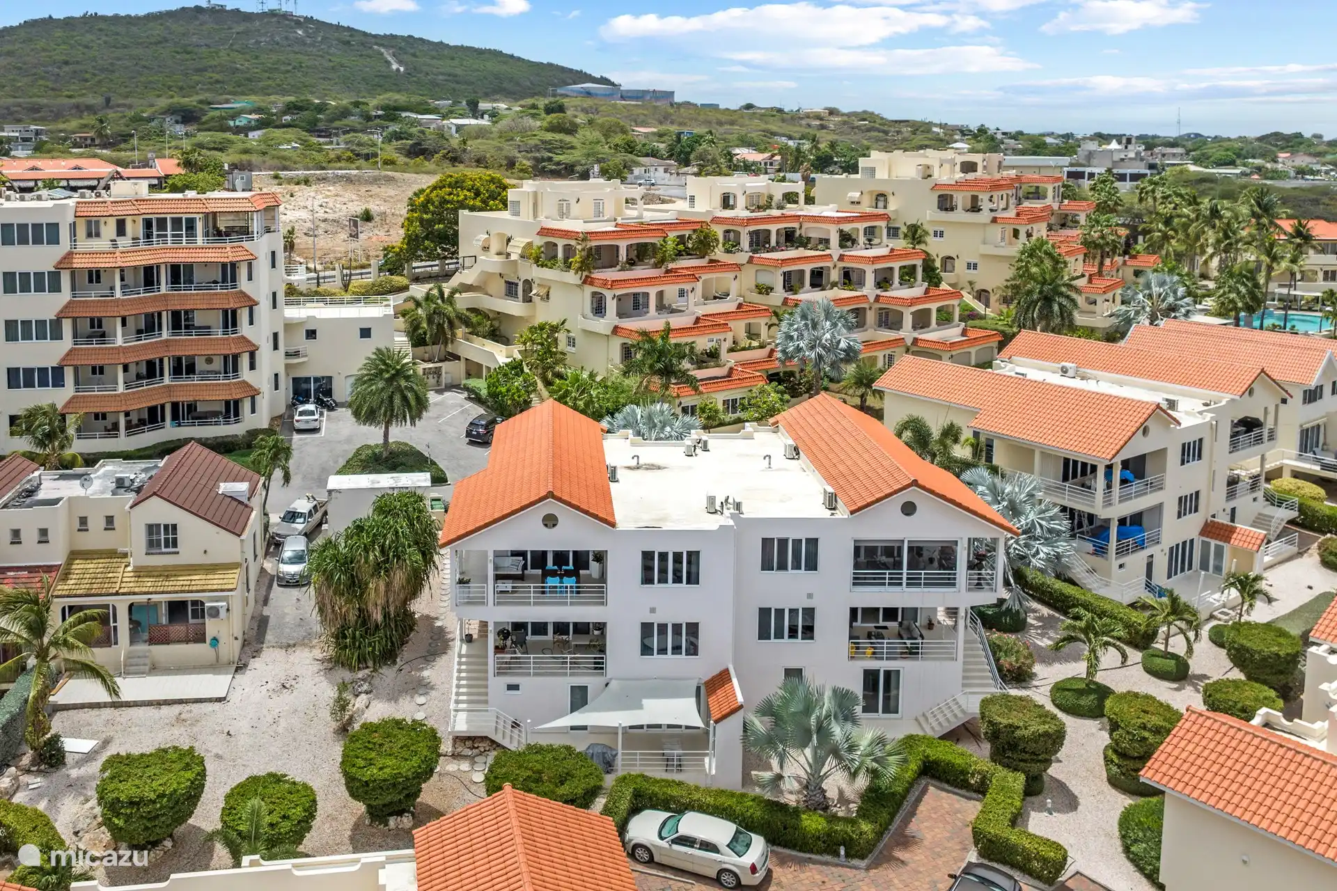 Cette photo d’ensemble montre la terrasse confortable, avec les chaises bleues caractéristiques de l’appartement - un endroit agréable pour se détendre