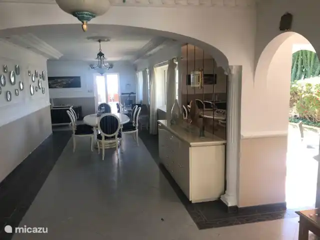 Villa del Sol - Entre Tu y Yo huren in Spanje, Costa del Sol, Benalmádena - villa De woonkamer met in het midden de eettafel, achteraan de deur naar het grote terras en het zwembad en links achteraan de zithoek. Vooraan rechts de deur naar het kleine terras en het grasperk.