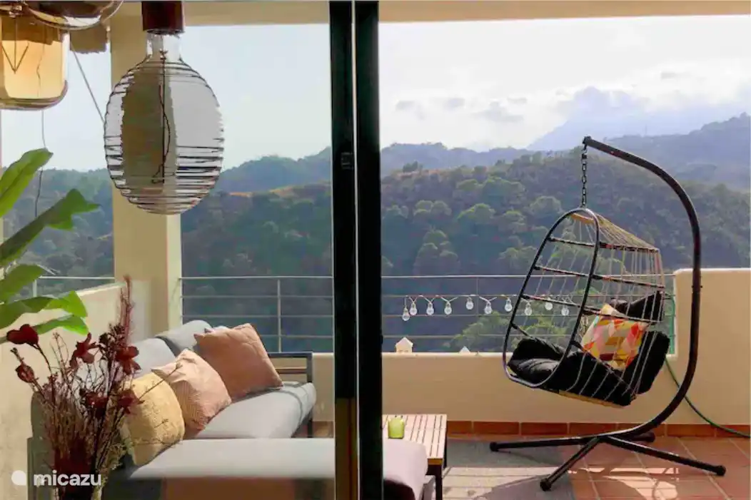 Terrasse ensoleillée avec coin salon, une table à manger spacieuse (6 personnes) et un fauteuil suspendu.