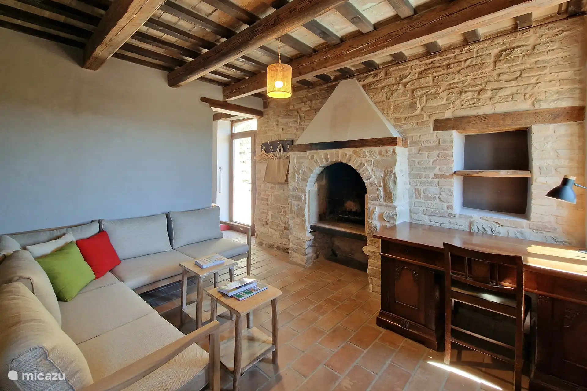 Auf diesem Foto sehen Sie ein schönes langes Sofa, auf dem Sie sitzen und ein Buch lesen, Ihren Lieblingsfilm ansehen oder den Kamin genießen können. Oder Sie arbeiten im Urlaub am Schreibtisch.