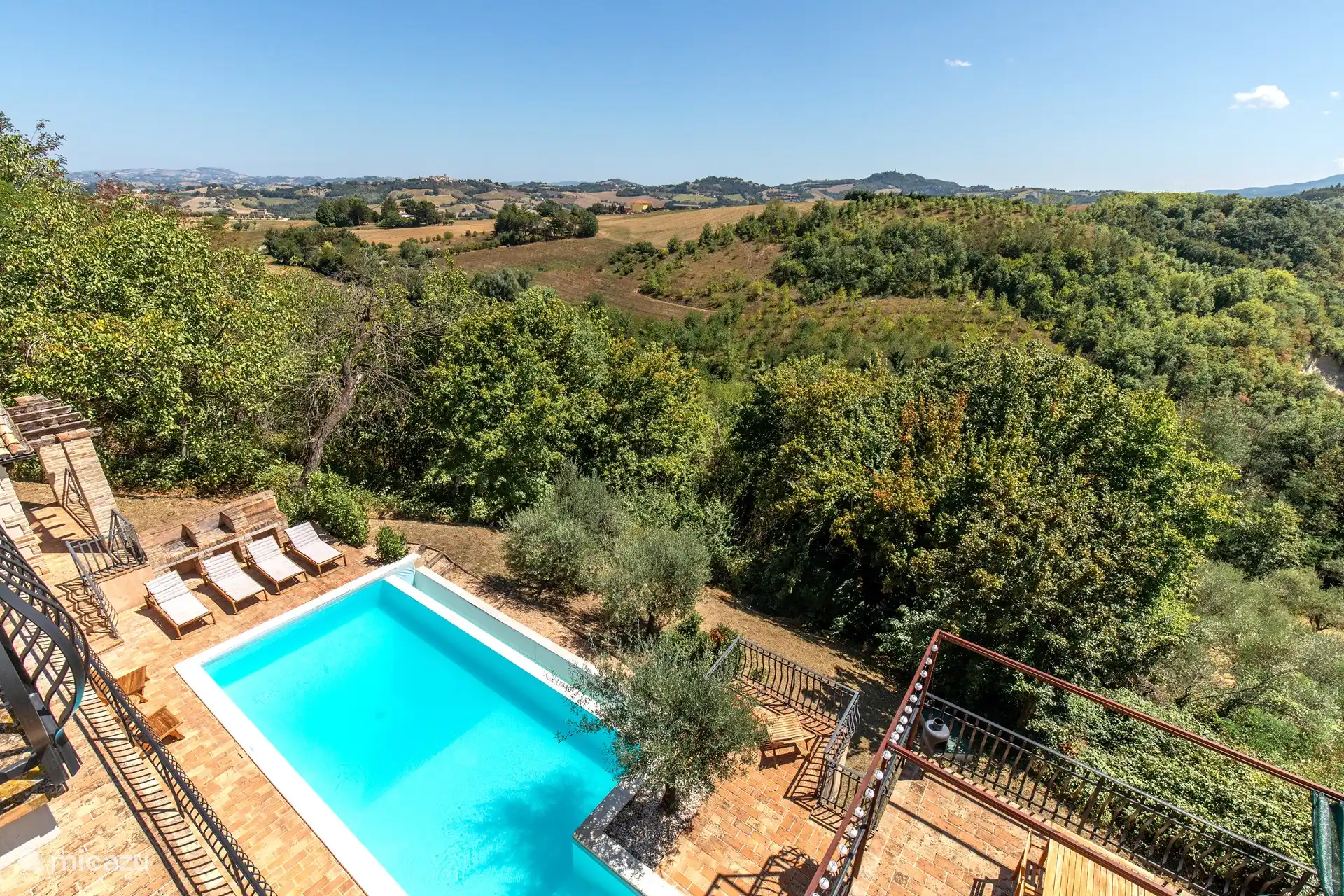 Ein kristallklares Schwimmbad, das sich perfekt in die umliegende Landschaft einfügt. Ein atemberaubender Panoramablick. Majestätisch erheben sich die grünen Hügel, während sich kleine Pfade zwischen den Bäumen und bunten Blumen schlängeln.