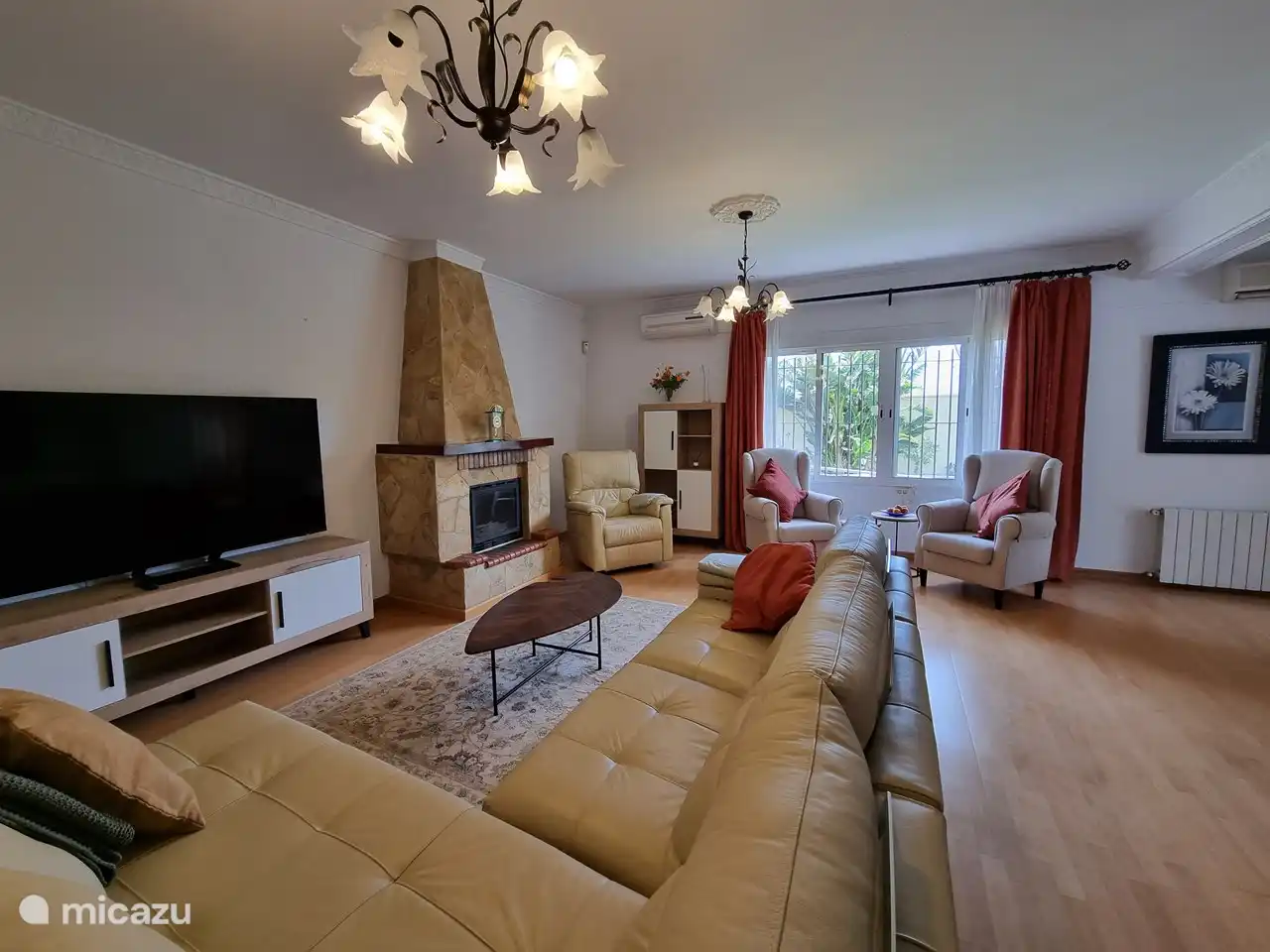 Wohnzimmer mit großem Luxussofa, Stühlen und einem großen Fernseher.