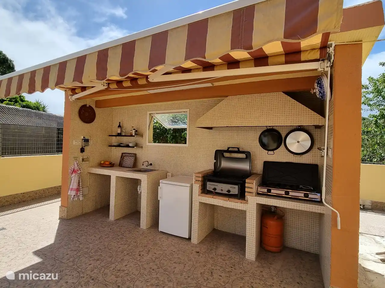 Die Außenküche mit Grill, Kühlschrank und einem zusätzlichen Kochfeld.