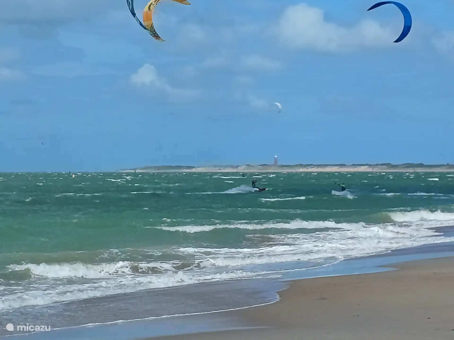 Kitesurf con un faro a lo lejos.