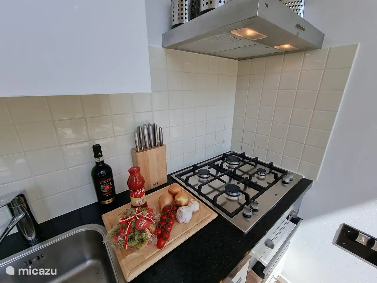 Moderne Küche mit Dunstabzugshaube, 4-Flammen-Gasherd, Backofen/Mikrowelle und Kühlschrank