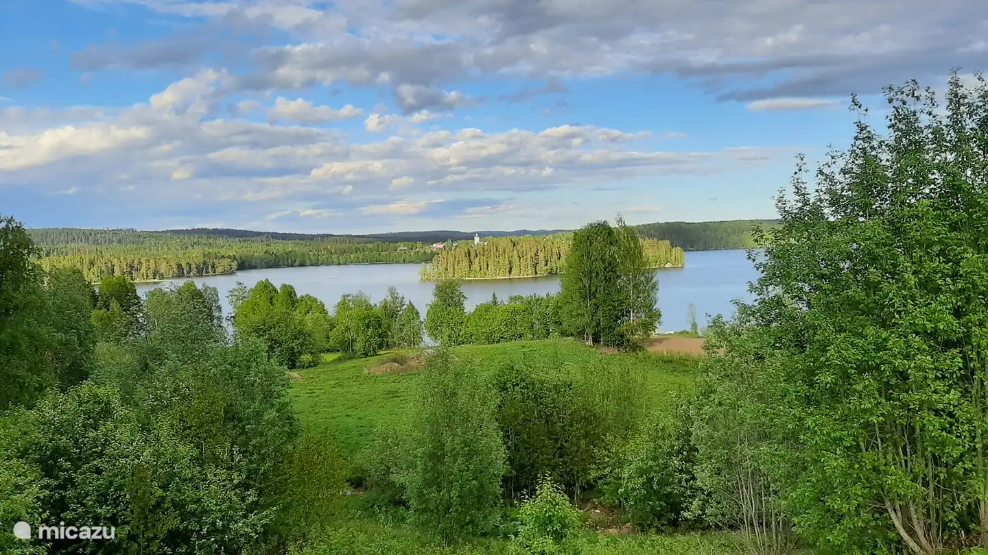 Zicht op het meer met een van de eilanden. Op de achtergrond het witte kerkje van Fjällsta