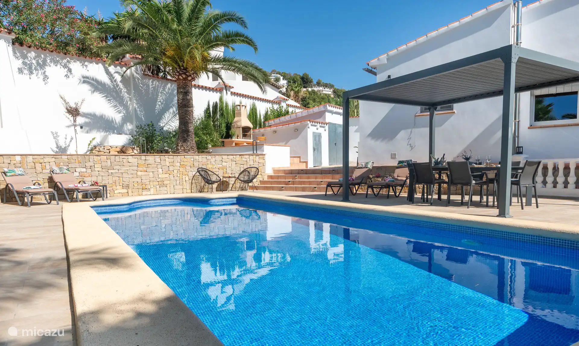 Privater Swimmingpool mit Sonnenliegen und Essbereich