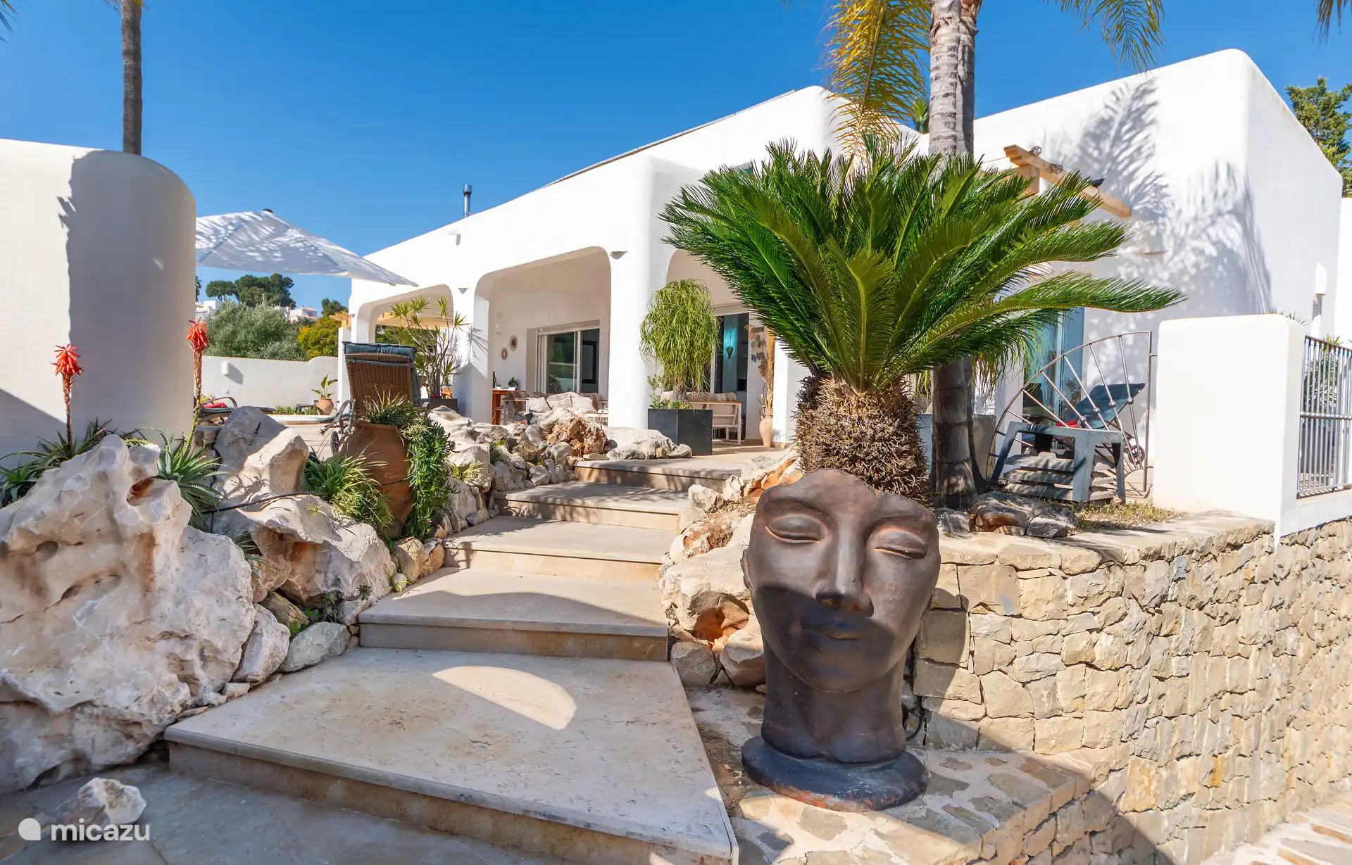 Ingang met steentuin en palmen