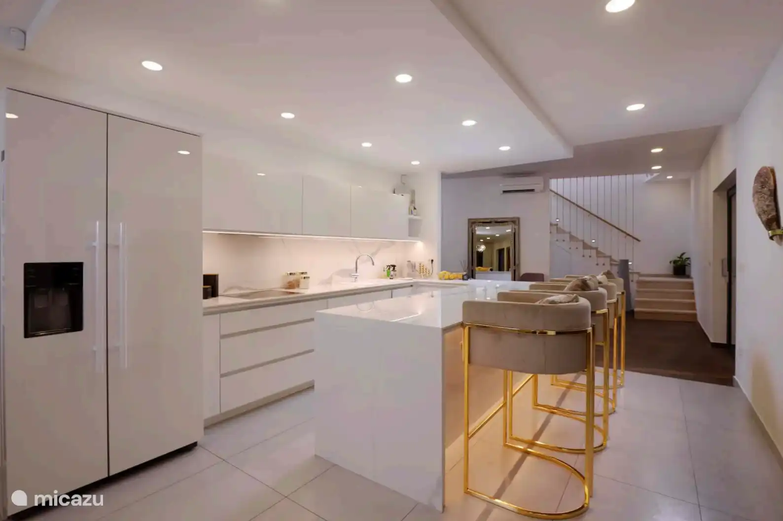 Lujosa cocina abierta que incluye nevera grande, congelador, lavavajillas, horno, microondas, vitrocerámica de 4 quemadores y vista a la terraza. 