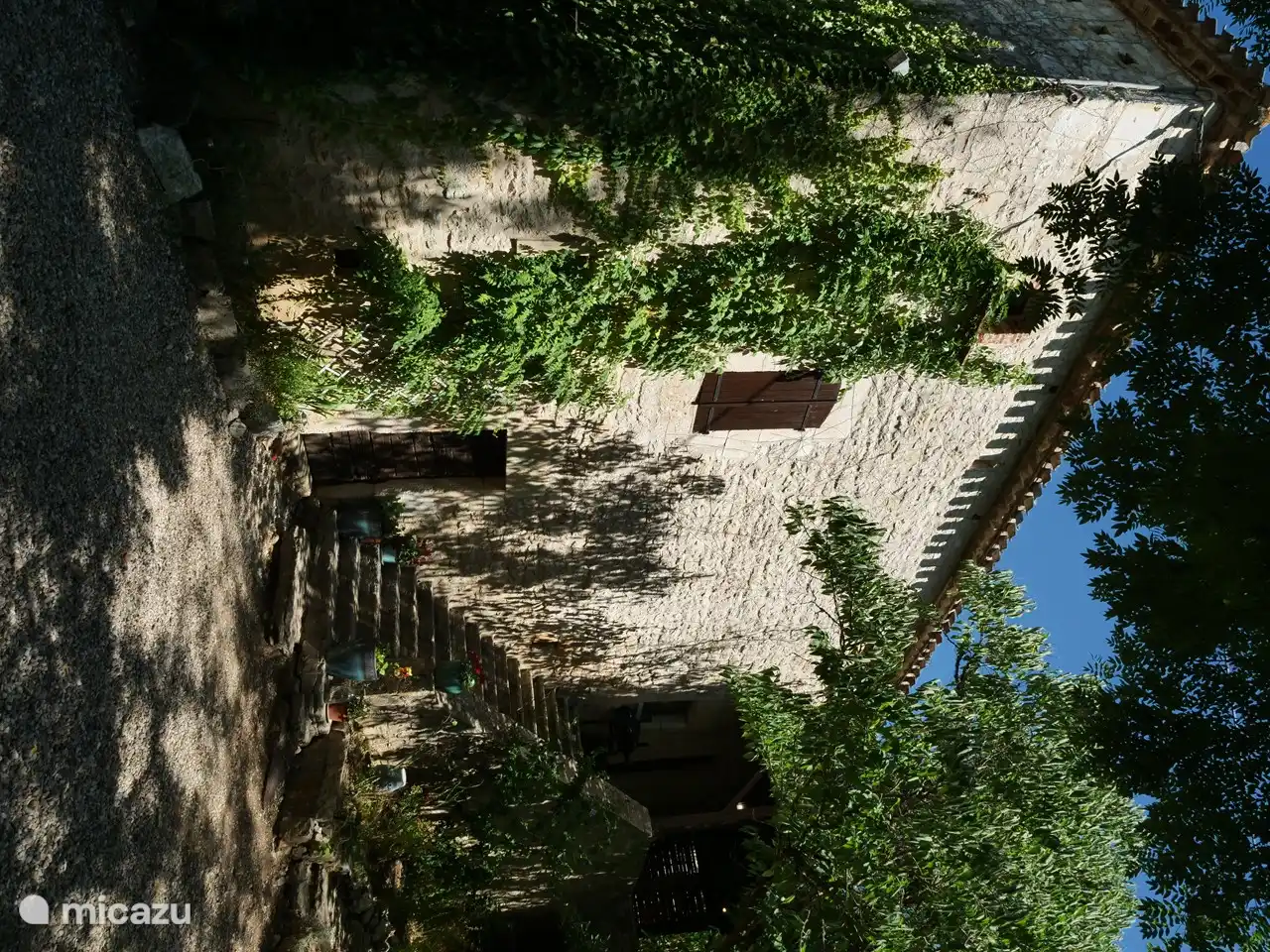 La vista lateral de la casa, con las grandes escaleras de piedra hacia la puerta principal y la terraza.