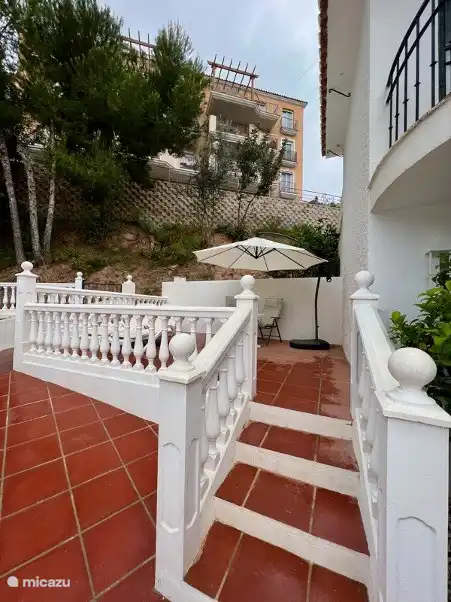 terraza lateral con tumbonas, mesa y sombrilla, forma parte del alojamiento