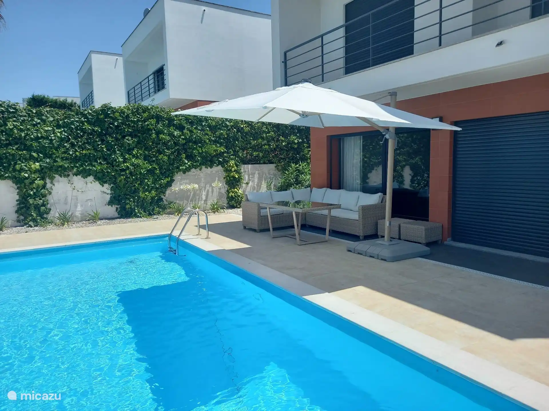 Op het terras staat een luxe loungeset en een kantelbare parasol.