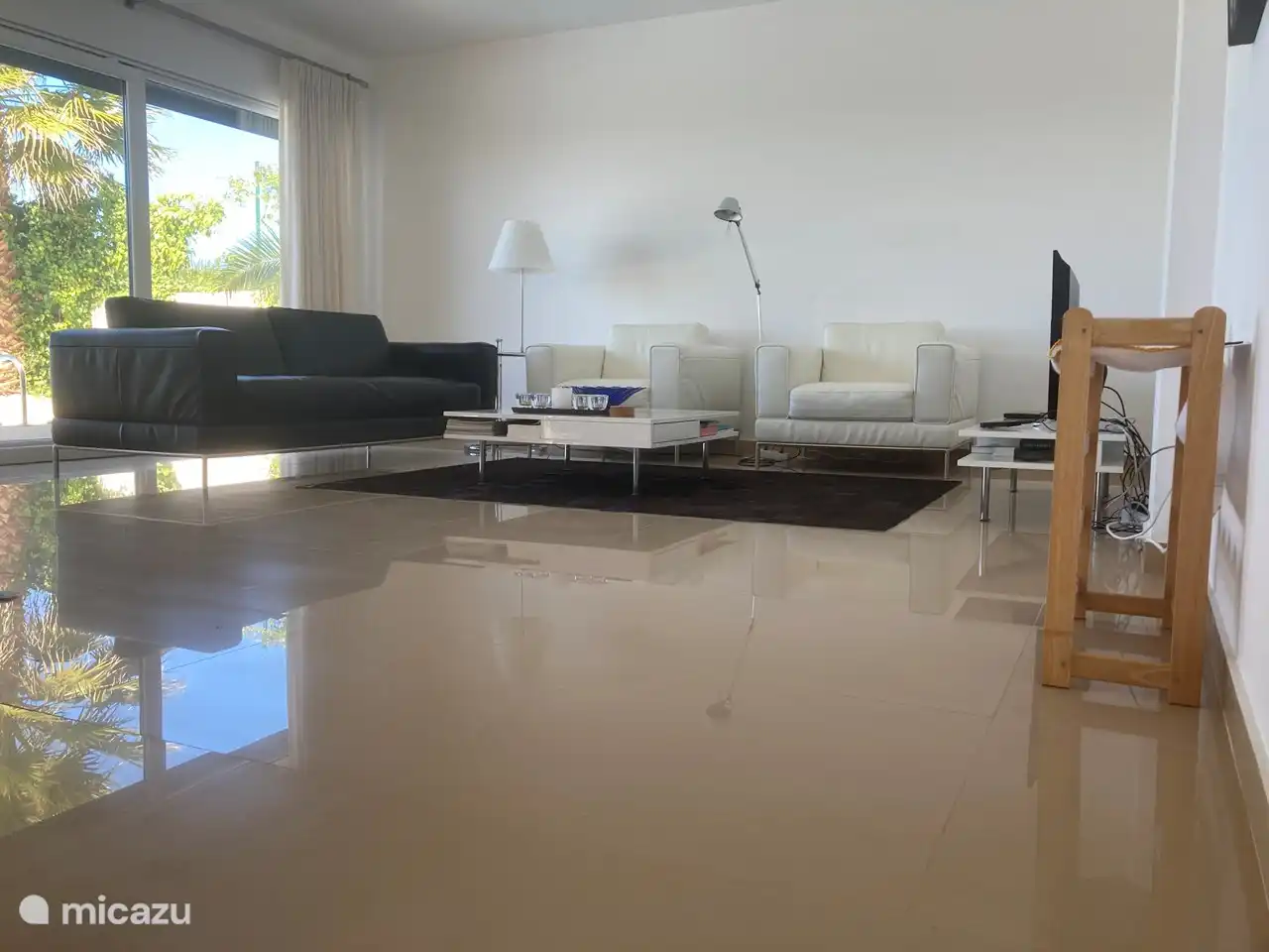 De zithoek in de kamer heeft een lederen bank en moderne designlampen. 
