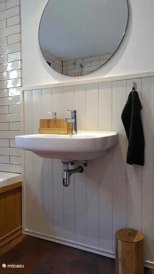 Photo du lavabo avec grand miroir rond dans la salle de bain