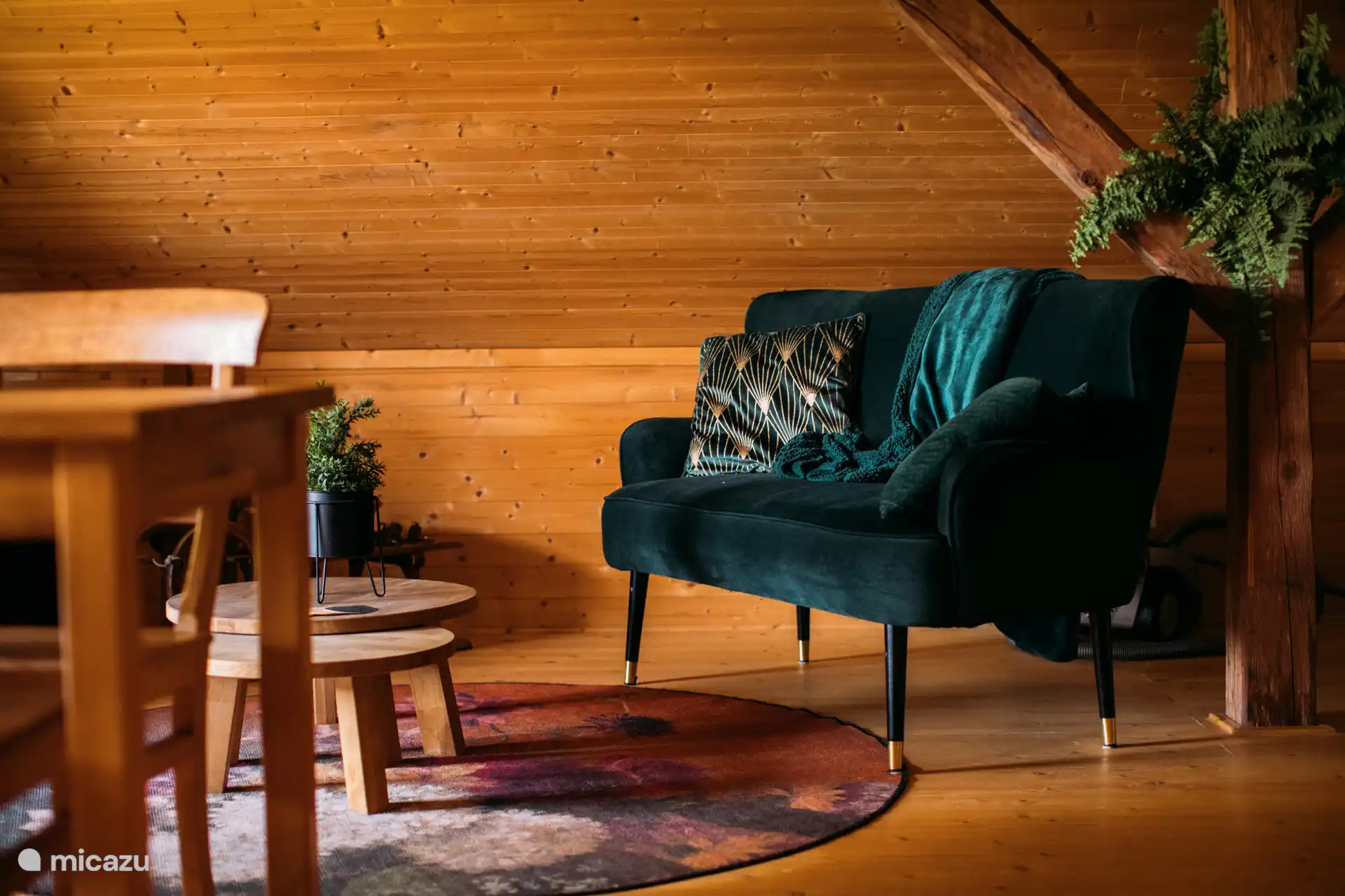 Gemütliche Sitzecke mit Samt-Zweisitzer, warmen Farben und stimmungsvollen Details – ideal zum Entspannen nach einem Tag in der Natur.