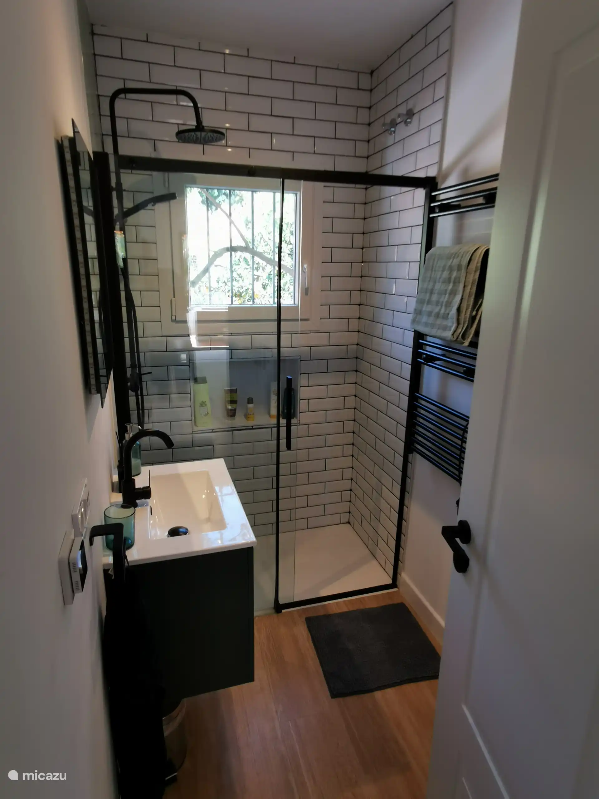 The small bathroom has a toilet and rain shower.